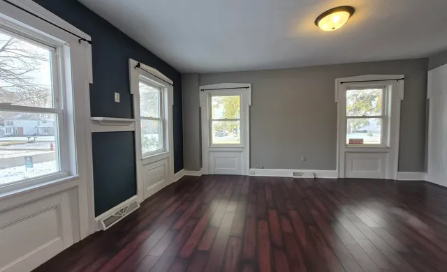 an empty room with wooden floor and windows