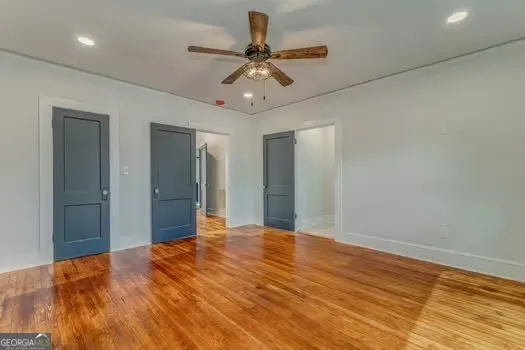 a view of a big room with wooden floor and a chandelier fan