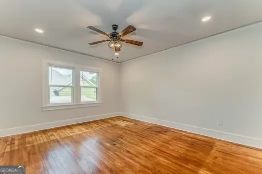 an empty room with wooden floor fan and windows
