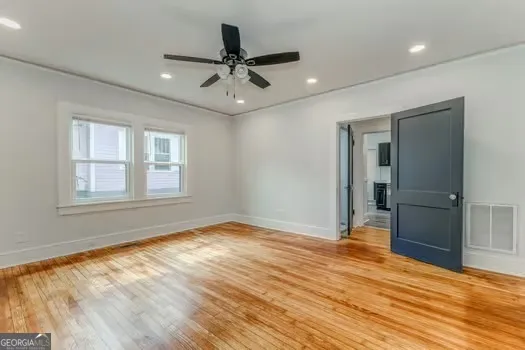 a view of empty room with wooden floor and fan