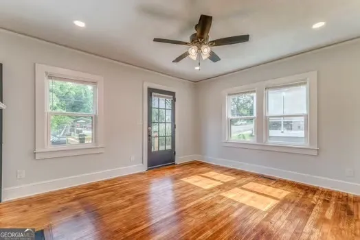 a view of an empty room with wooden floor and a window