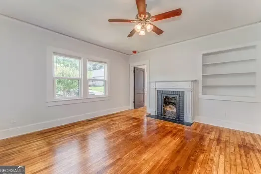 a view of empty room with fan and a fireplace