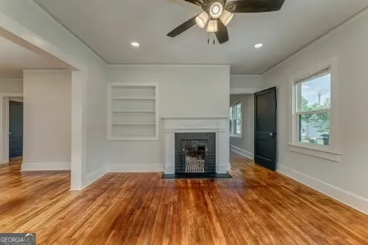 an empty room with wooden floor a ceiling fan and windows