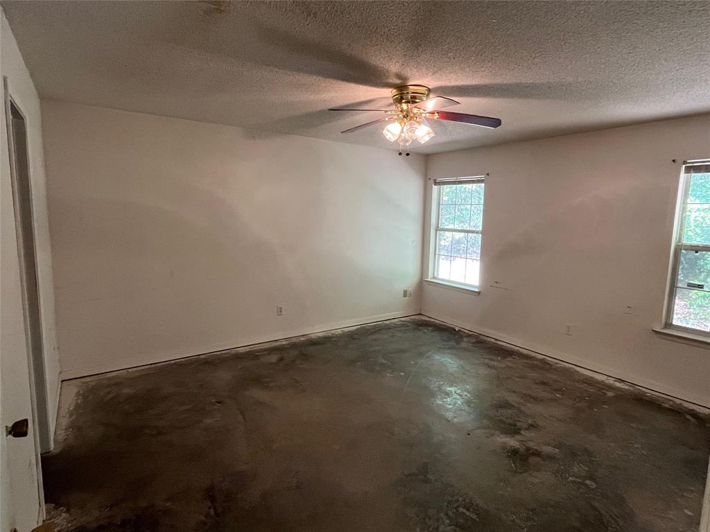 105 East Foggle Street Athens, TX 75751 - Photo 14 of 21 an empty room with windows and chandelier fan