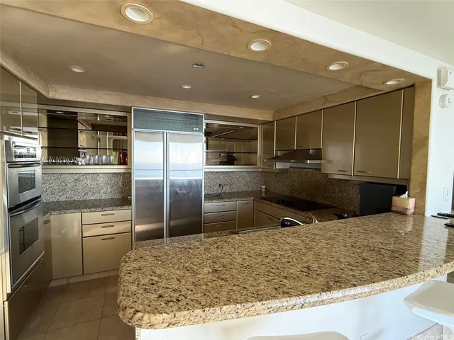 a kitchen with stainless steel appliances kitchen island granite countertop a sink stove and refrigerator