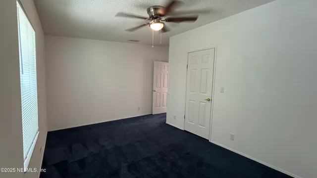 an empty room with wooden floor and fan