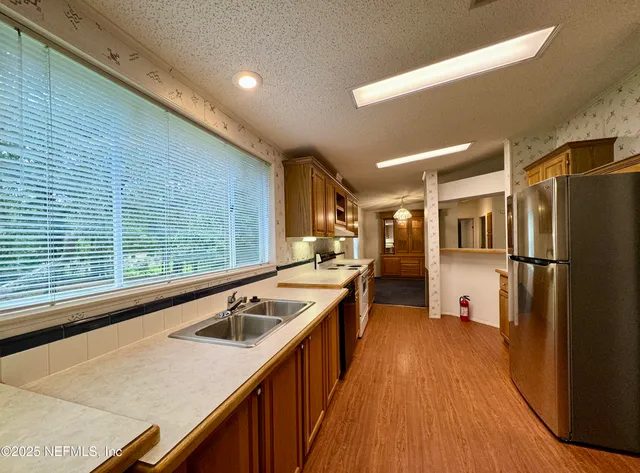a kitchen with a sink a refrigerator and wooden floor