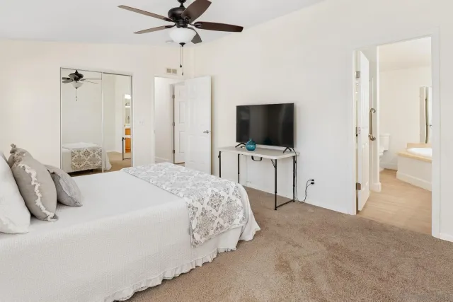 a bedroom with a bed and a flat tv screen on dresser