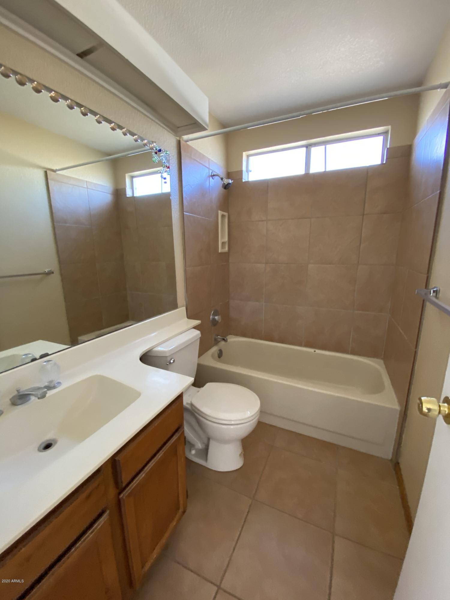 6932 West Paradise Drive Peoria, AZ 85345 - Photo 11 of 15 a bathroom with a sink a toilet a mirror and bathtub