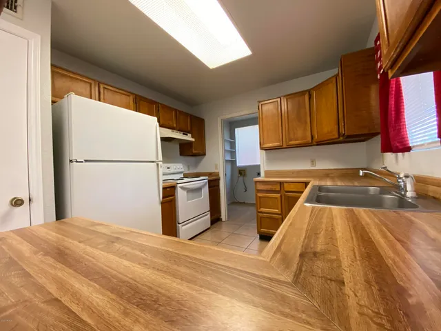 a kitchen with a refrigerator a stove top oven a sink dishwasher and wooden cabinets