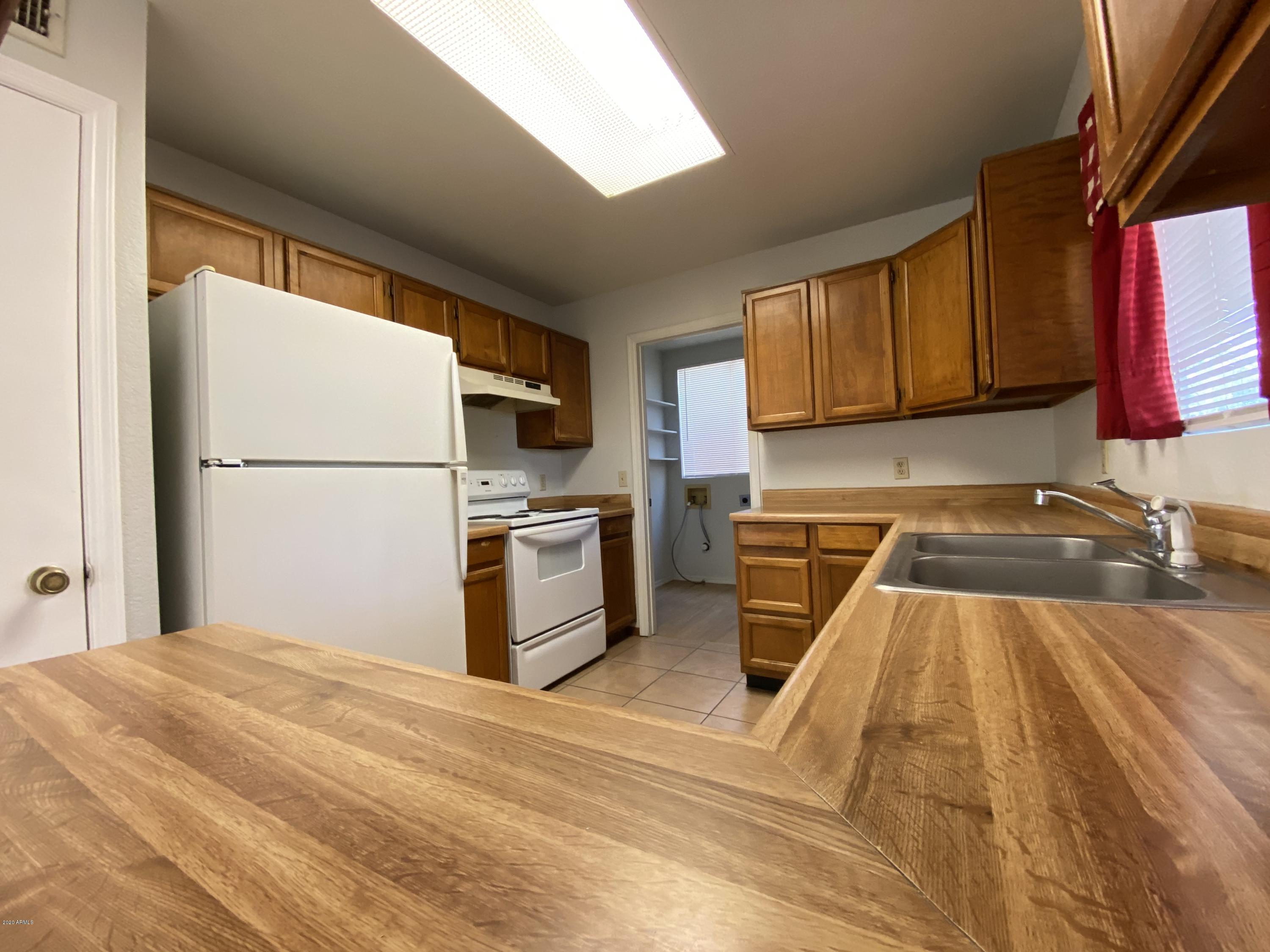 6932 West Paradise Drive Peoria, AZ 85345 - Photo 7 of 15 a kitchen with a refrigerator a stove top oven a sink dishwasher and wooden cabinets