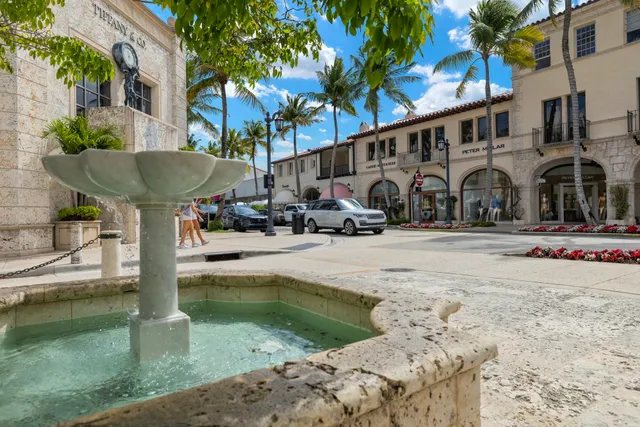 a front view of multi story residential apartment building with yard and retail shops