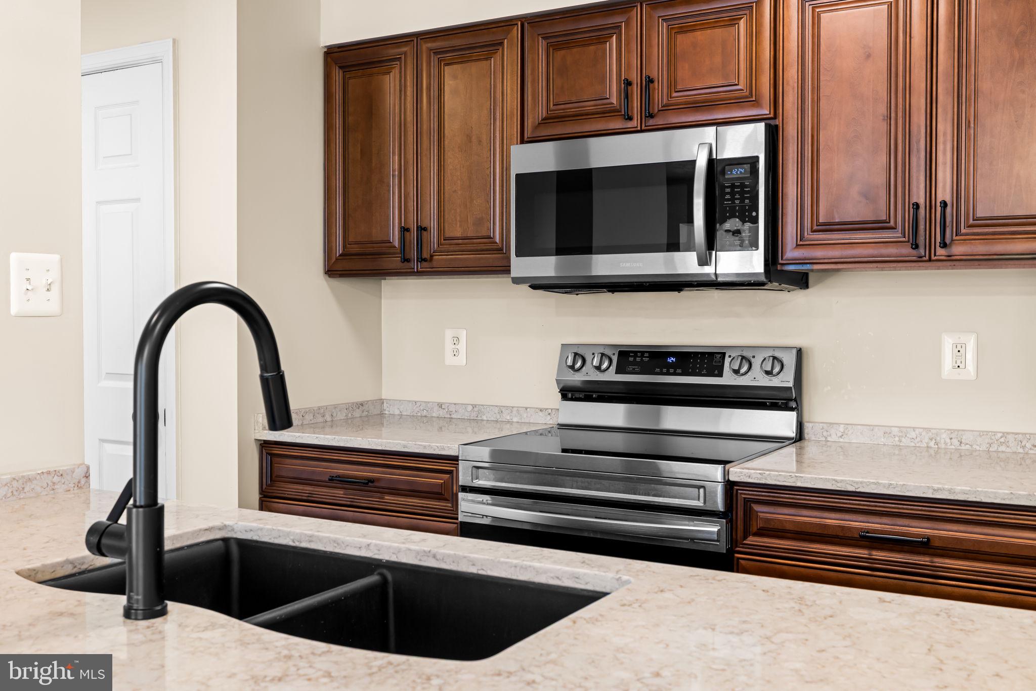 41 Laurel Path Court, Unit 5 Baltimore, MD 21236 - Photo 11 of 32 a kitchen with stainless steel appliances kitchen island granite countertop a stove and a microwave with cabinets