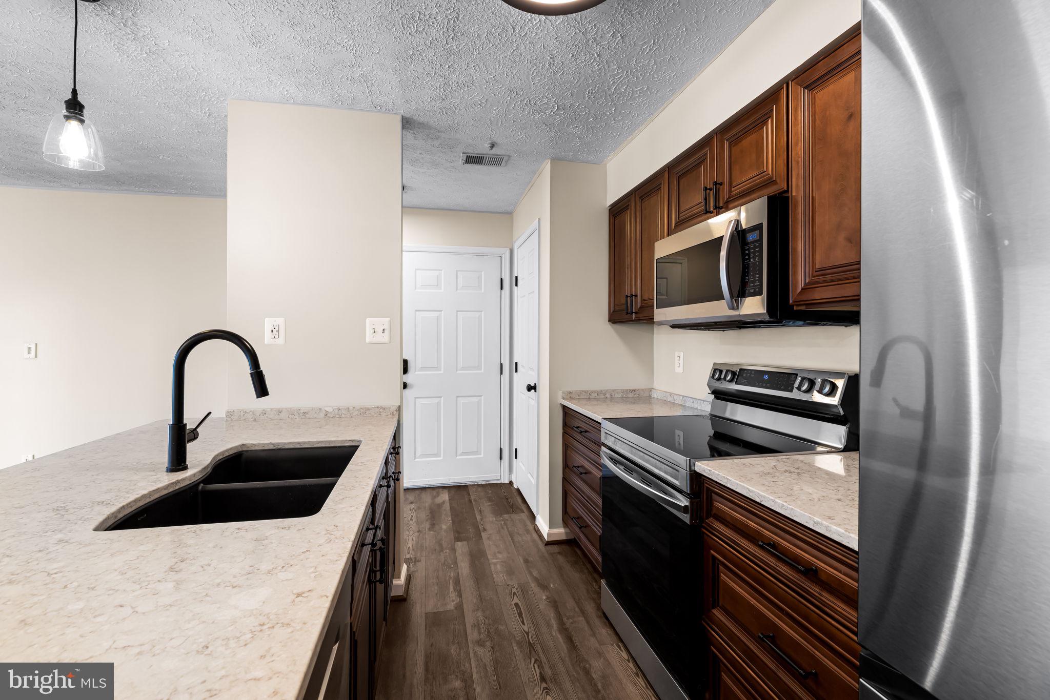 41 Laurel Path Court, Unit 5 Baltimore, MD 21236 - Photo 12 of 32 a kitchen with stainless steel appliances a microwave a sink and white cabinets