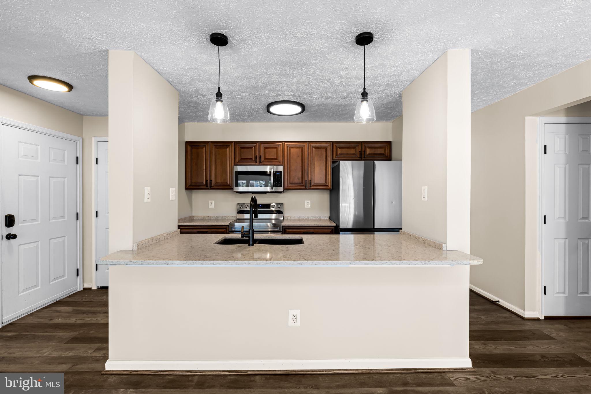 41 Laurel Path Court, Unit 5 Baltimore, MD 21236 - Photo 10 of 32 a kitchen with stainless steel appliances a refrigerator a sink dishwasher a stove and white cabinets with wooden floor