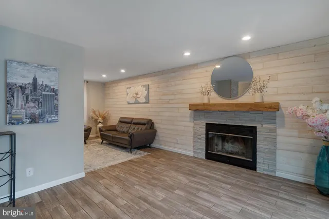 a view of an empty room with wooden floor fireplace and a window