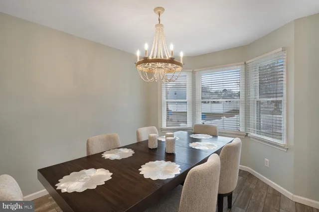 a dining room with wooden floor a chandelier a wooden table and chairs