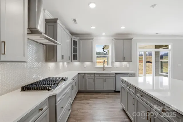 a large kitchen with stainless steel appliances granite countertop a lot of counter space and wooden floors