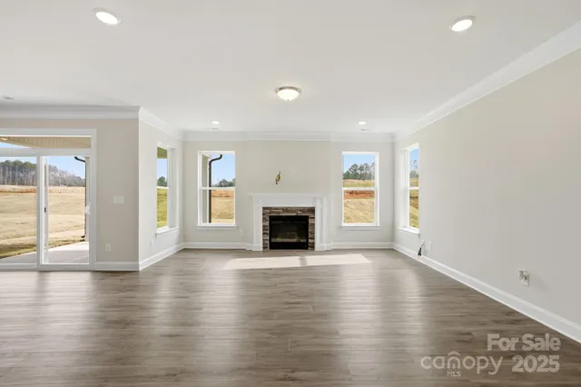 an empty room with wooden floor fireplace and windows
