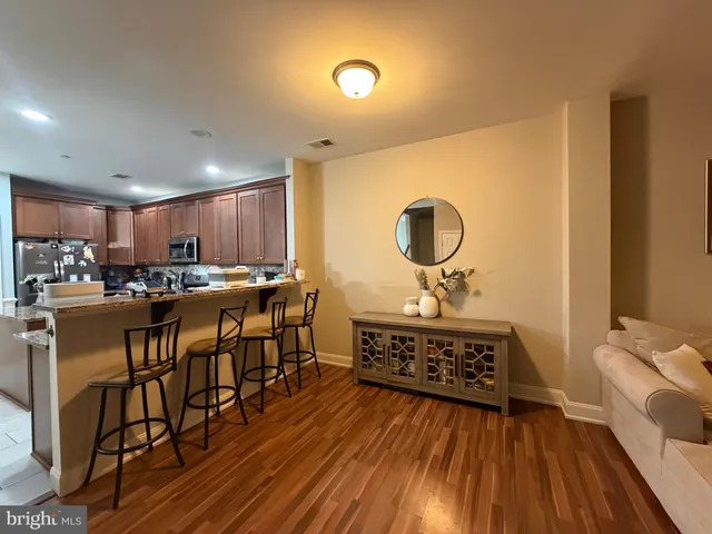 a view of a kitchen with kitchen island a sink wooden floor and stainless steel appliances