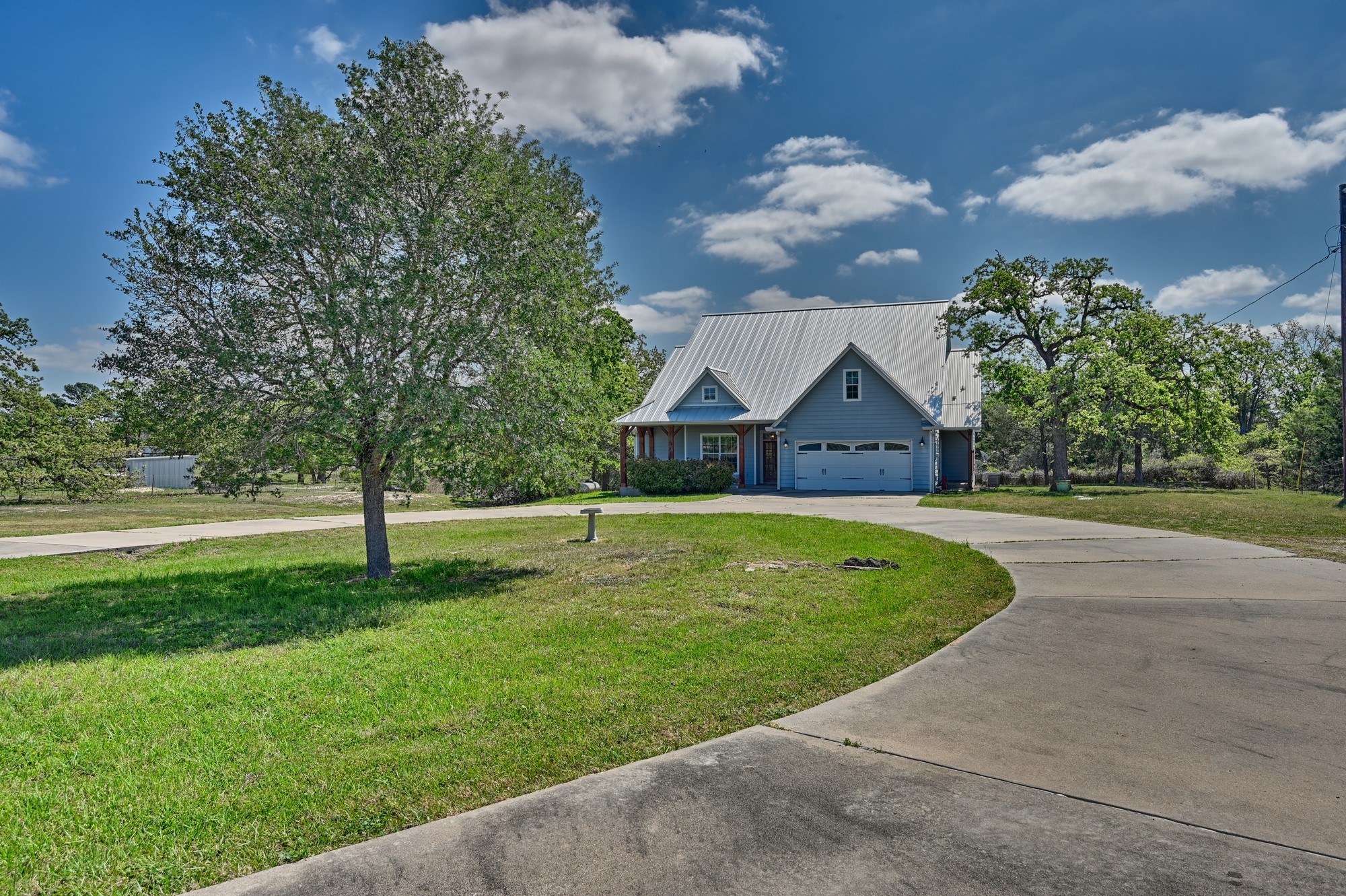 350 Owl Creek Road Giddings, TX 78942 - Photo 11 of 29 View of front of home featuring a front lawn, curved driveway, and a metal roof