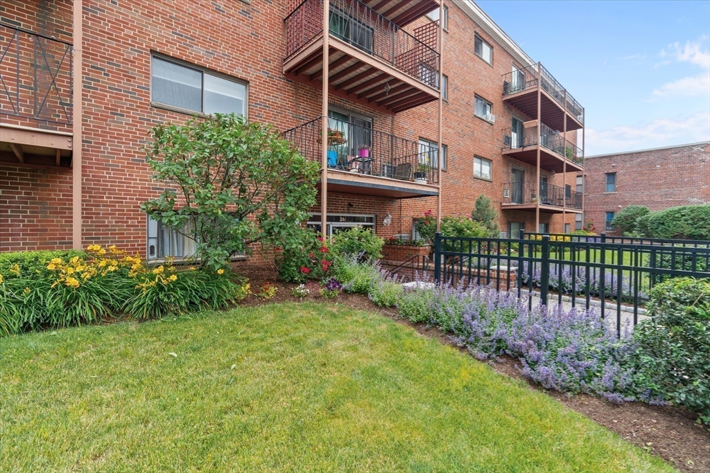 26 Waverly Street, Unit 410 Boston, MA 02135 - Photo 23 of 32 a view of a brick house with a small yard plants and a large tree