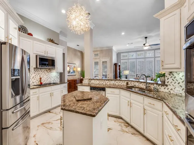 a large kitchen with granite countertop lots of counter top space and stainless steel appliances