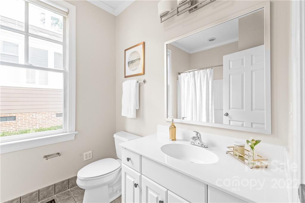 2208 Club Road Charlotte, NC 28205 - Photo 13 of 25 a bathroom with a granite countertop toilet a sink a mirror and a window
