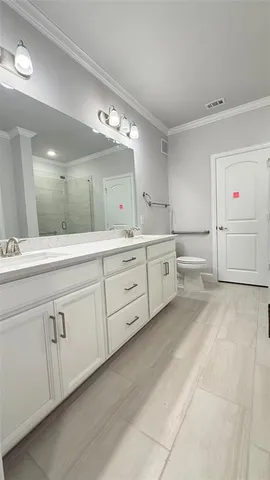 a spacious en suite bathroom with a double vanity sink and mirror