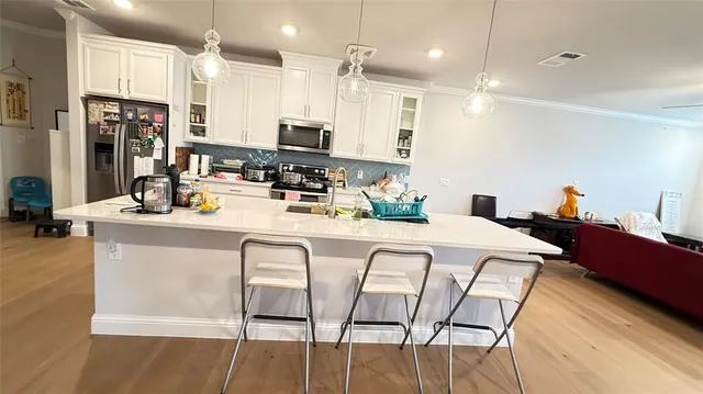 a kitchen with stainless steel appliances kitchen island granite countertop a table chairs refrigerator and microwave