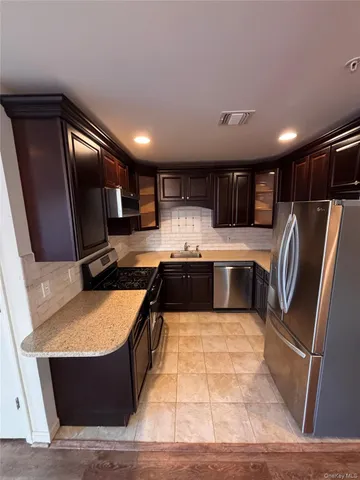 a kitchen with stainless steel appliances granite countertop a stove a sink dishwasher a refrigerator and a oven with wooden floor