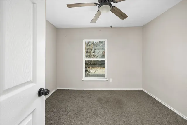 an empty room with a window and a ceiling fan