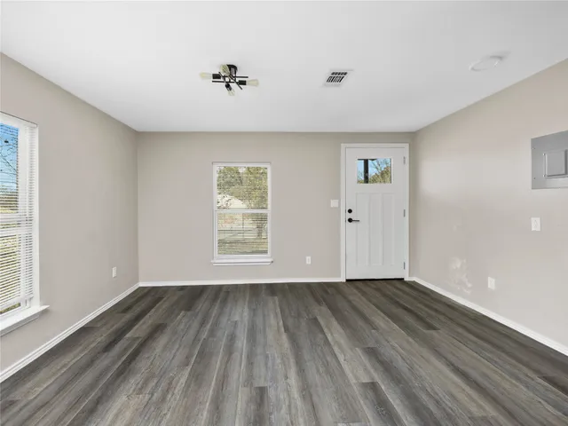 a view of an empty room with wooden floor and a window