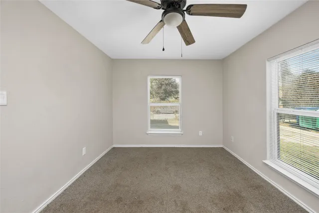 an empty room with a window and a ceiling fan