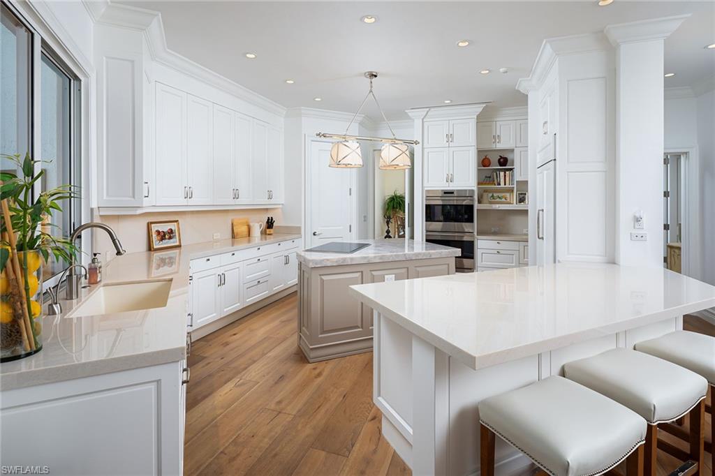 6975 Green Tree Drive Naples, FL 34108 - Photo 7 of 33 Kitchen featuring a kitchen island, light wood-style floors, decorative light fixtures, white cabinetry, and recessed lighting