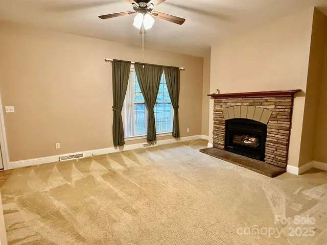 an empty room with fireplace fan and windows