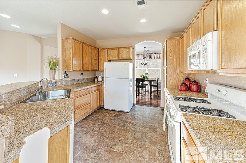 10442 Rockport Lane Reno, NV 89521 - Photo 8 of 17 a kitchen with a stove a sink dishwasher a refrigerator and cabinets with wooden floor