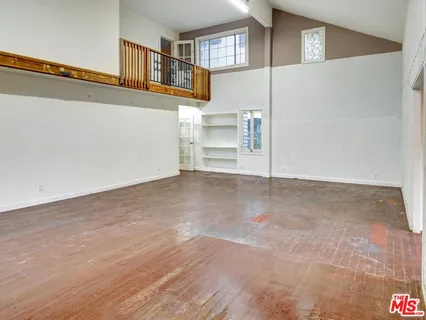 a view of an empty room with wooden floor and windows