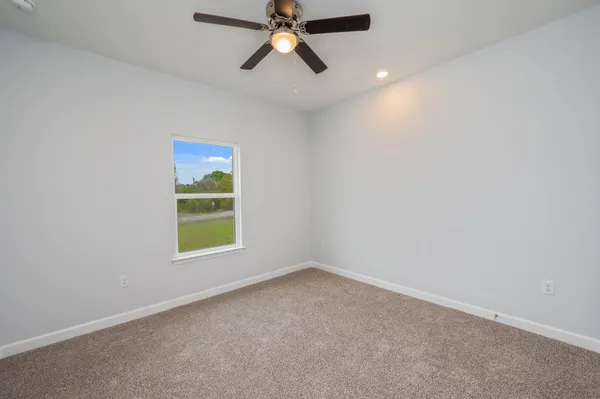 an empty room with a window and a ceiling fan