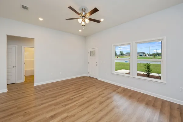 a view of an empty room with a window and wooden floor