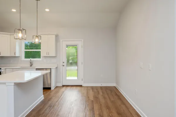 a view of a kitchen with a sink and dishwasher with wooden floor