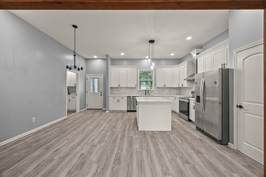 9469 Lakeland Loop Quinlan, TX 75474 - Photo 10 of 31 a large kitchen with a refrigerator a sink dishwasher a stove and white cabinets with wooden floor