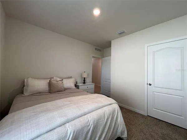 a large white bed sitting in a bedroom next to a window