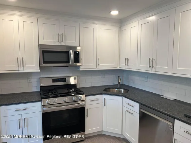 a kitchen with granite countertop white cabinets and stainless steel appliances