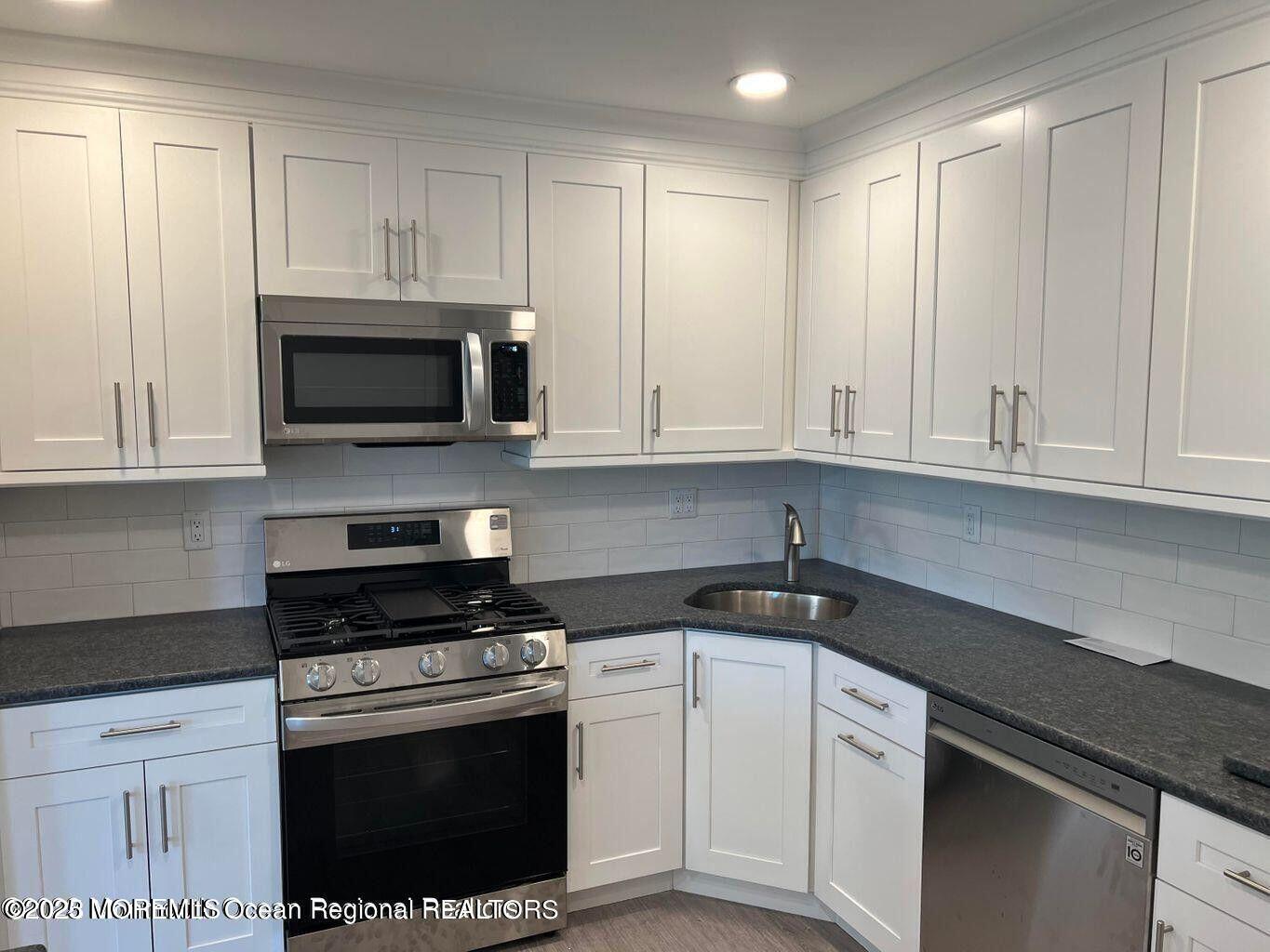 a kitchen with granite countertop white cabinets and stainless steel appliances