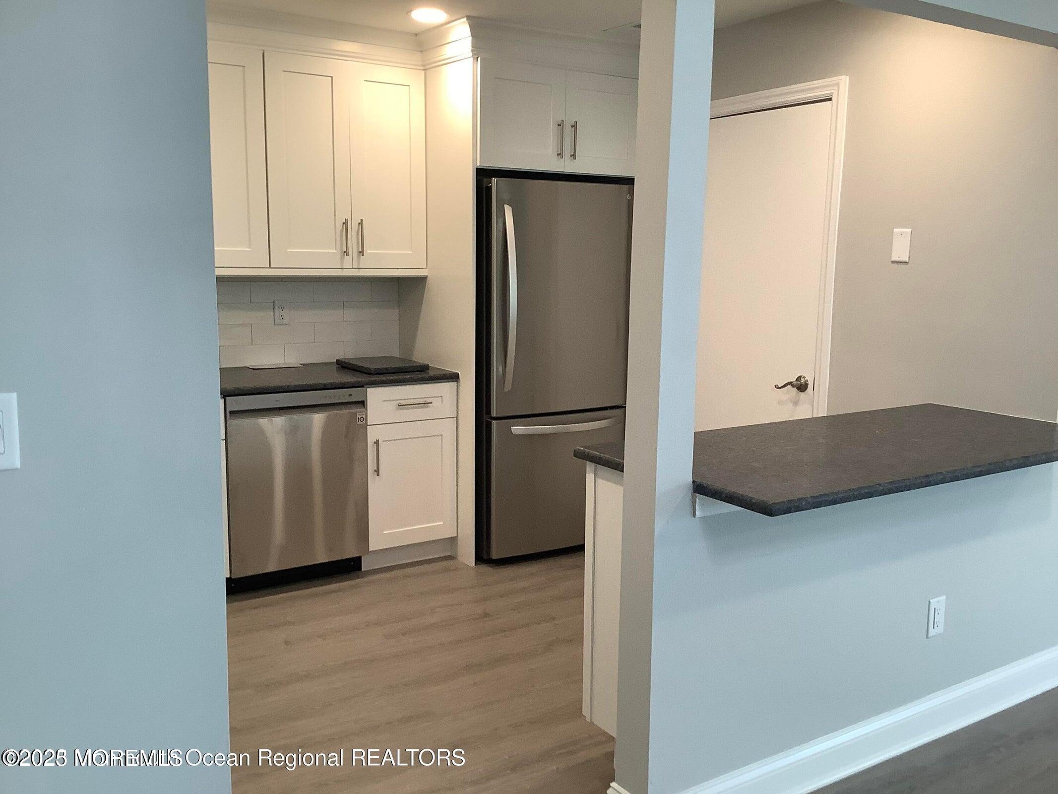 506 Harding Road, Unit 6 Freehold, NJ 07728 - Photo 6 of 21 a kitchen with stainless steel appliances granite countertop a refrigerator a stove and a sink with wooden floor