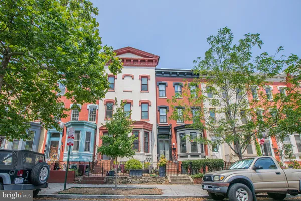 a front view of a building with lot of cars and trees