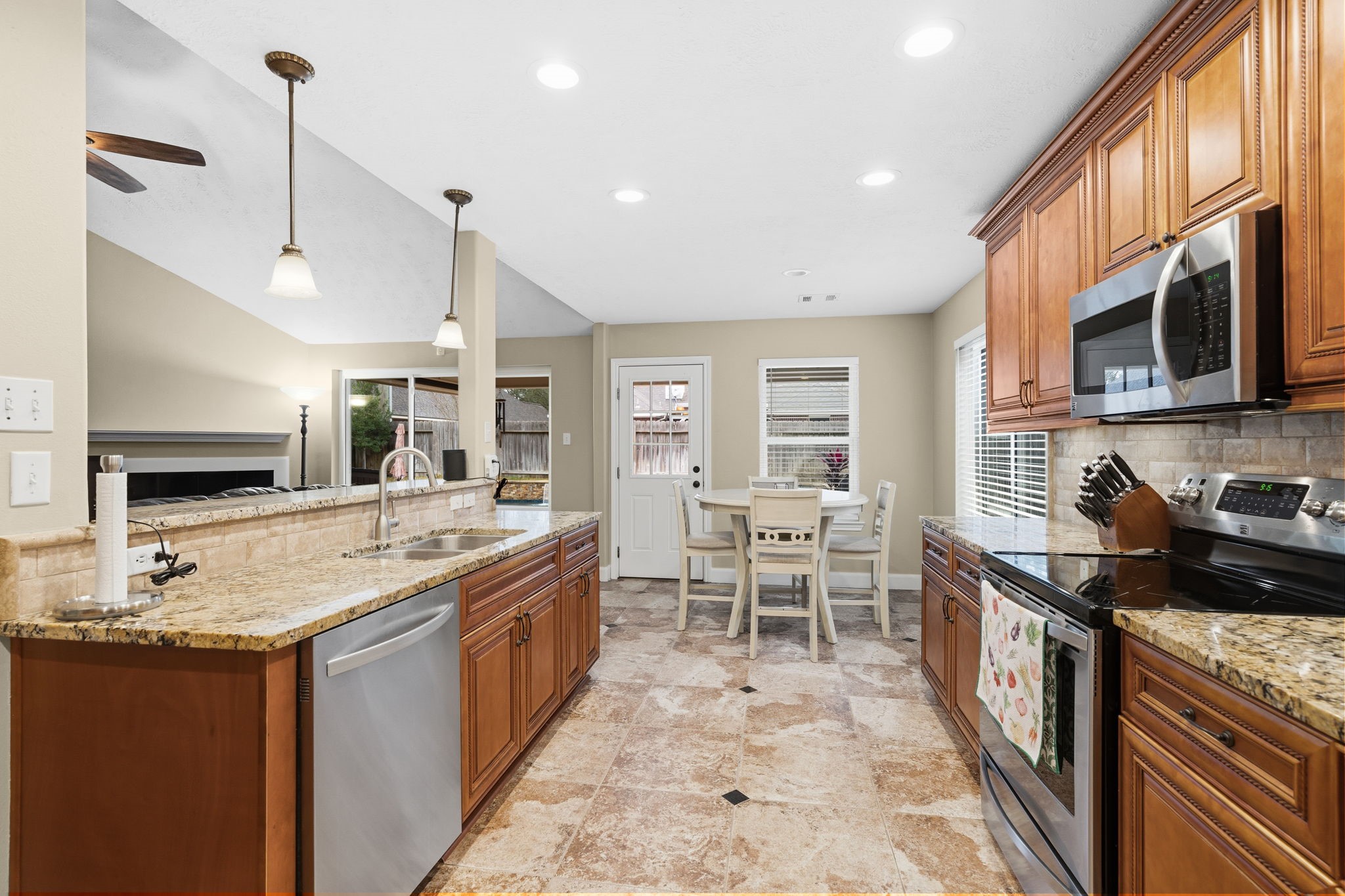 15319 Court Green Trail Cypress, TX 77433 - Photo 14 of 44 a kitchen with stainless steel appliances granite countertop a stove top oven a sink dishwasher a dining table and chairs with wooden floor