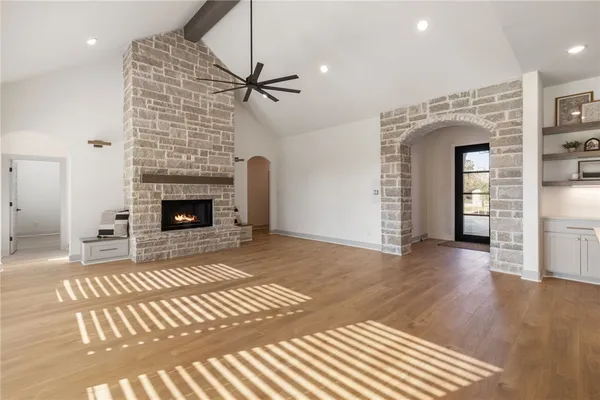 a view of an empty room with wooden floor fireplace and a window