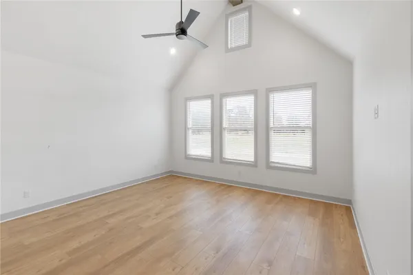 an empty room with wooden floor fan and windows